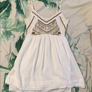 A white minidress with gold beads on it